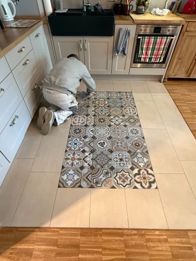 Ein Handwerker verlegt Fliesen auf dem Küchenboden.